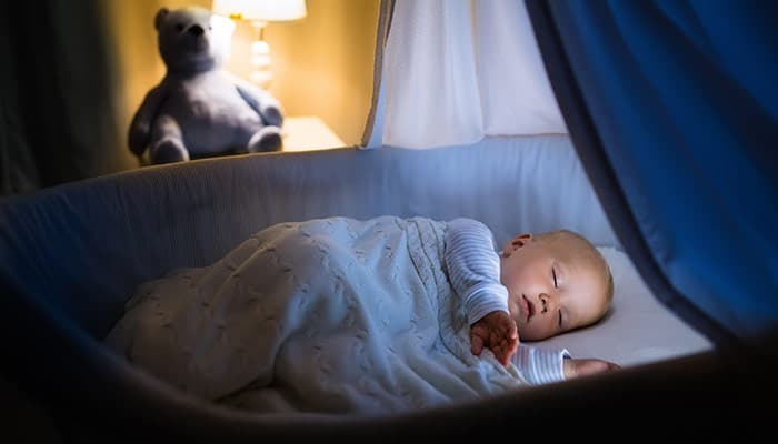 Adorable baby sleeping in blue bassinet