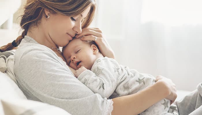 Loving mom carying of her newborn baby at home