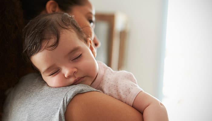 Mother cuddling sleeping baby daughter