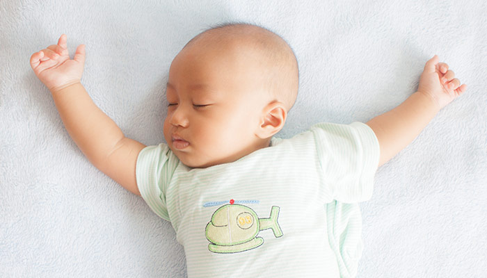 sleeping baby on back white bed