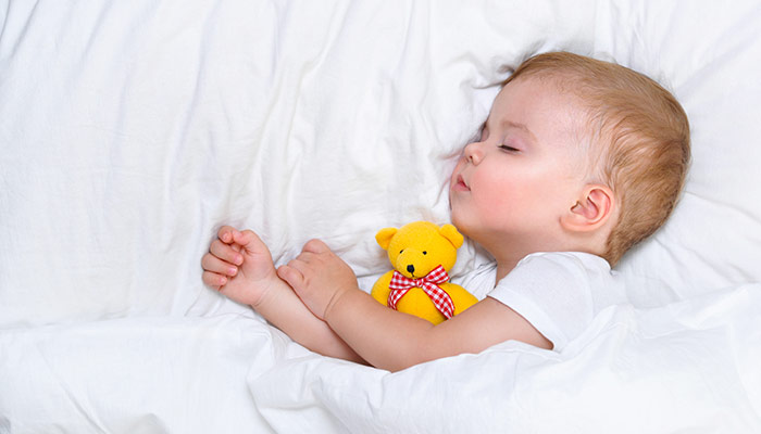 Year old child sleeps in white bed